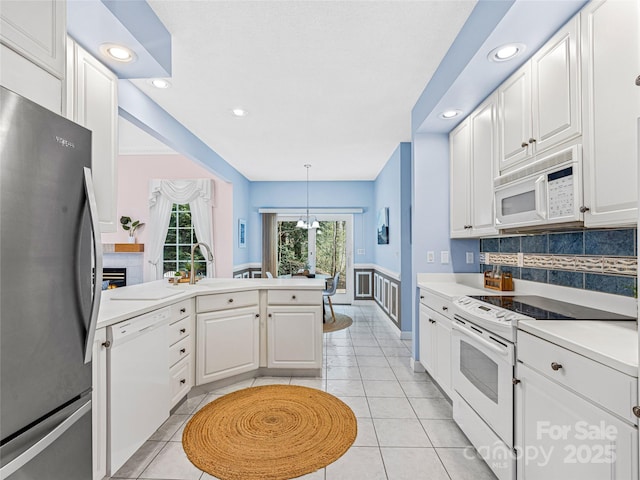 kitchen with white appliances, white cabinetry, light countertops, and pendant lighting