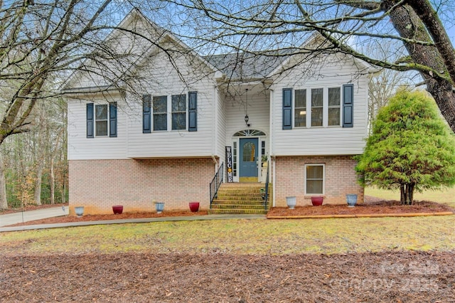 raised ranch featuring brick siding and a front lawn