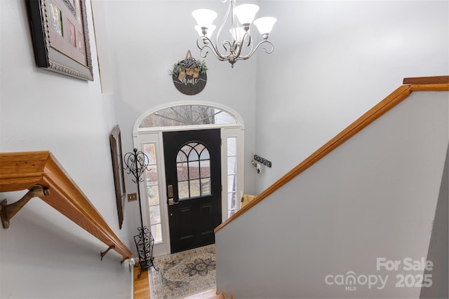 entrance foyer with a chandelier, a high ceiling, light wood finished floors, and stairs