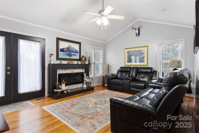 living room featuring french doors, a fireplace, vaulted ceiling, and wood finished floors