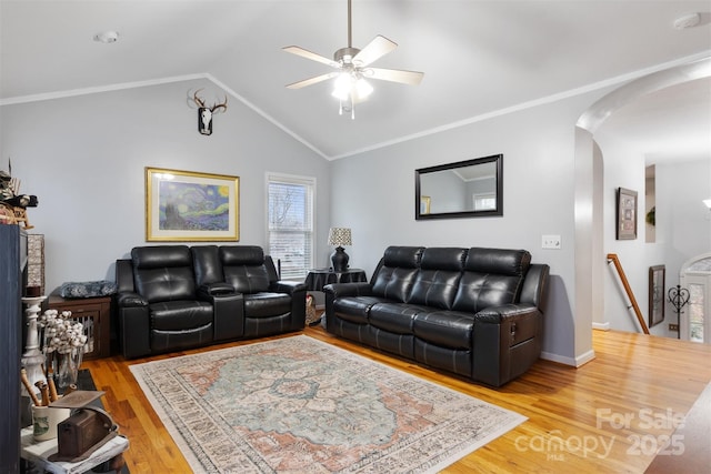 living room featuring arched walkways, light wood finished floors, lofted ceiling, and ornamental molding