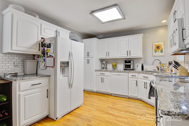 kitchen featuring white appliances, white cabinetry, a sink, and light wood-style flooring