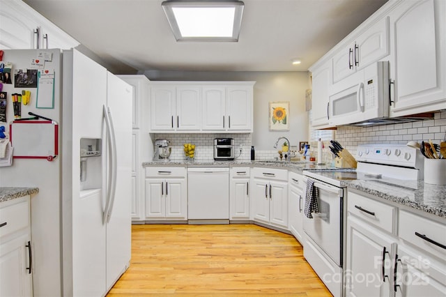 kitchen featuring white appliances, white cabinets, a sink, and light wood finished floors