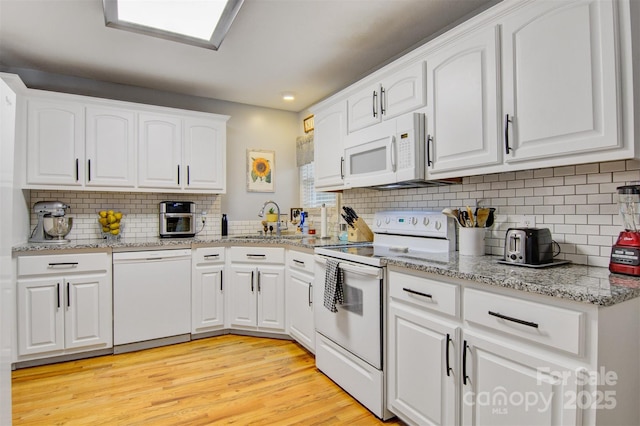 kitchen featuring light wood-type flooring, white appliances, white cabinets, and a sink