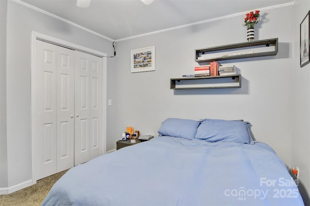 carpeted bedroom featuring ceiling fan, crown molding, baseboards, and a closet