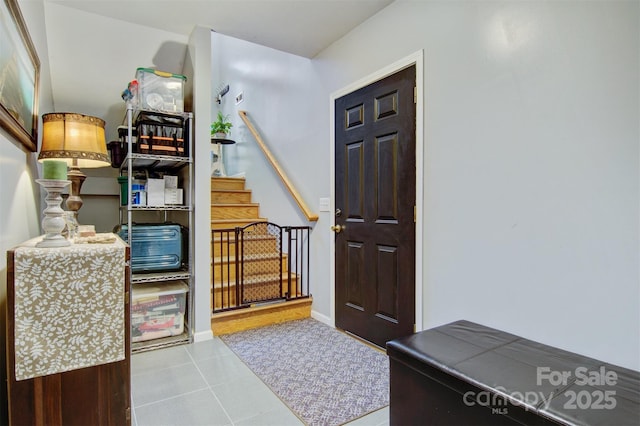 entrance foyer with light tile patterned floors, stairway, and baseboards