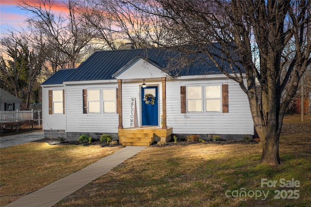 view of front of property with a chimney, metal roof, crawl space, and a front yard