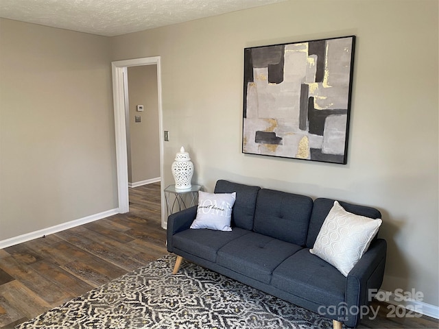 living room featuring a textured ceiling, baseboards, and wood finished floors