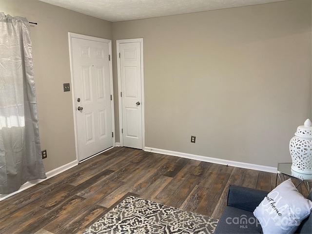 foyer featuring a textured ceiling, baseboards, and wood finished floors