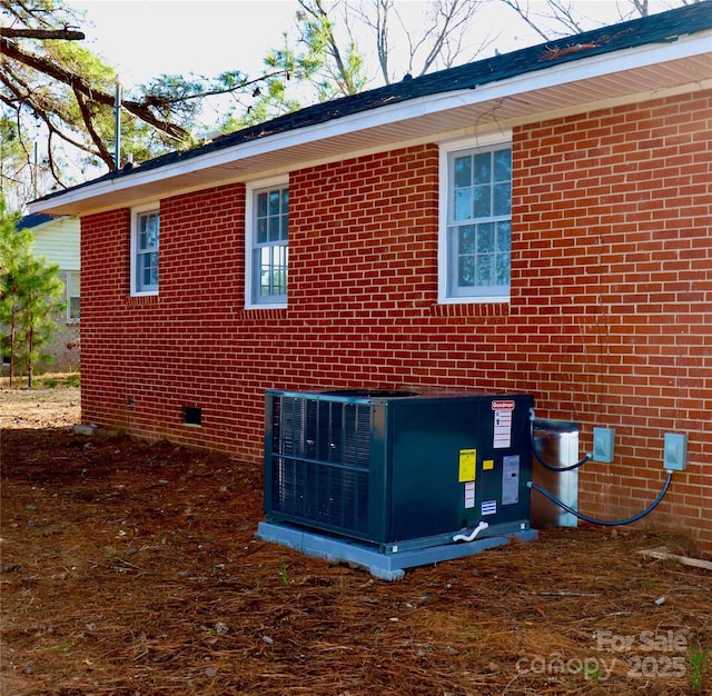 view of side of home with central air condition unit and brick siding