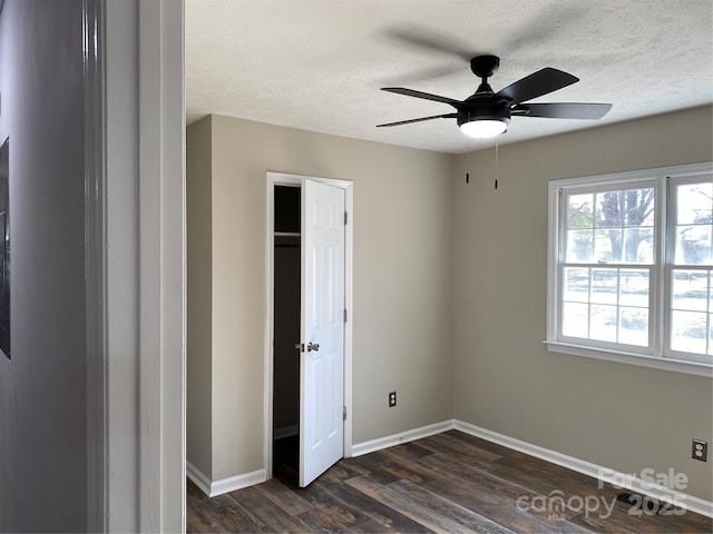 unfurnished bedroom featuring dark wood finished floors, a textured ceiling, baseboards, and ceiling fan