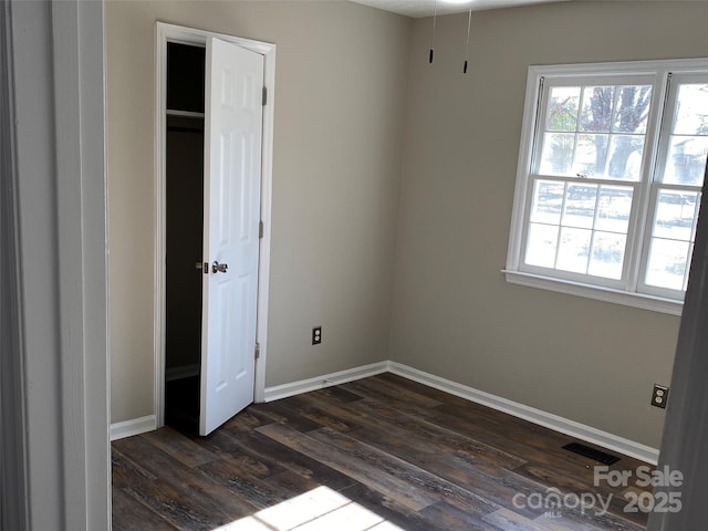 unfurnished bedroom with baseboards, visible vents, and dark wood-style flooring