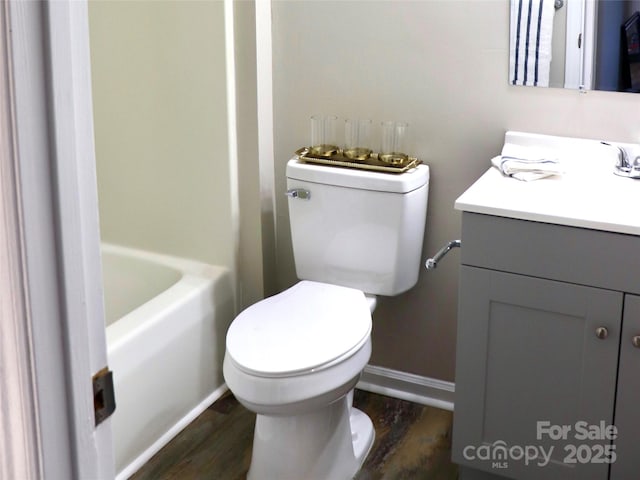 full bathroom featuring toilet, a bathtub, wood finished floors, and vanity