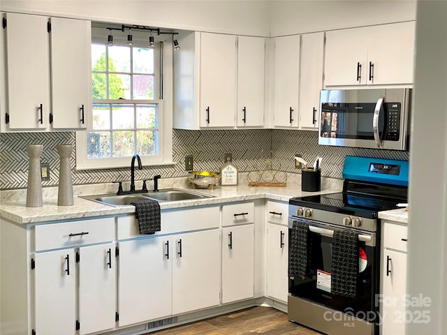 kitchen with stainless steel appliances, light countertops, a sink, and decorative backsplash