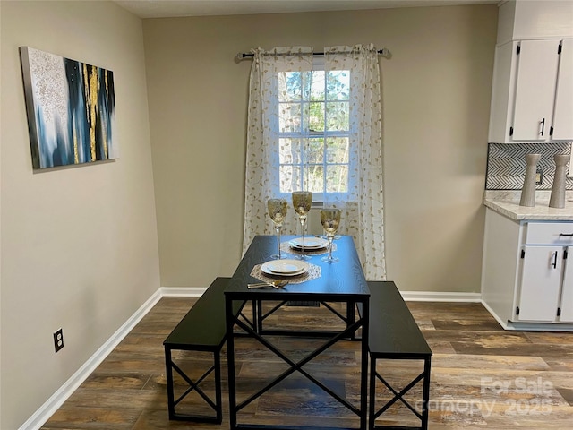 dining space featuring dark wood-style floors and baseboards