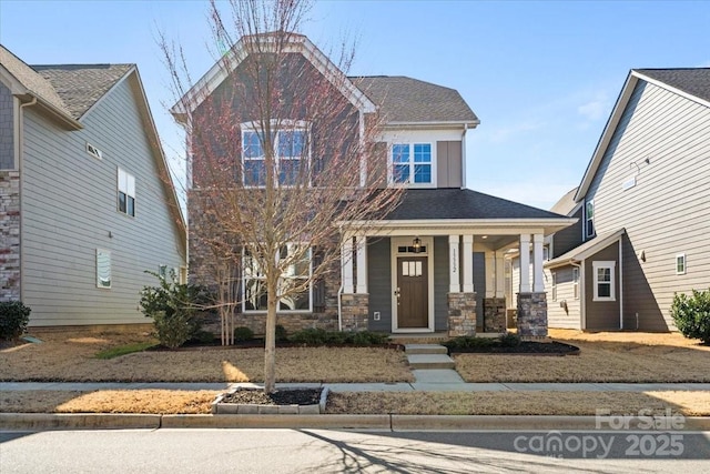 craftsman-style home with stone siding, a shingled roof, and a porch