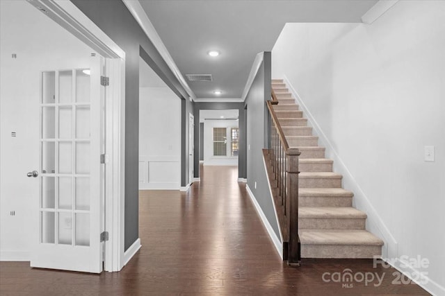 interior space featuring dark wood-style floors, crown molding, recessed lighting, a decorative wall, and stairs