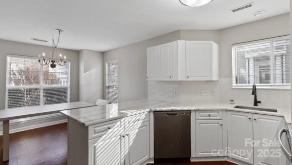 kitchen featuring hanging light fixtures, stainless steel dishwasher, white cabinets, a sink, and a peninsula