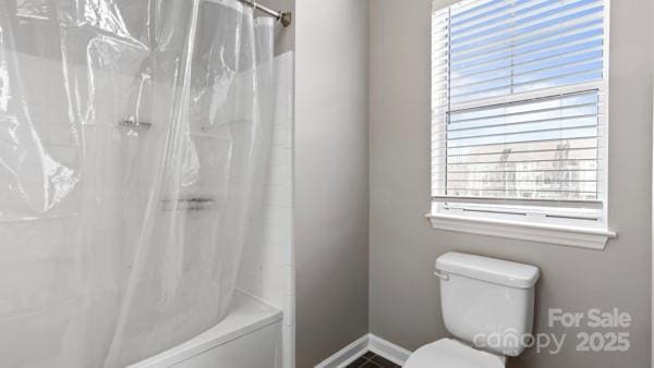 full bathroom with baseboards, toilet, and shower / bath combo with shower curtain