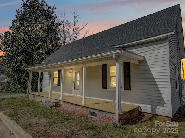 view of front of house with crawl space, covered porch, and roof with shingles