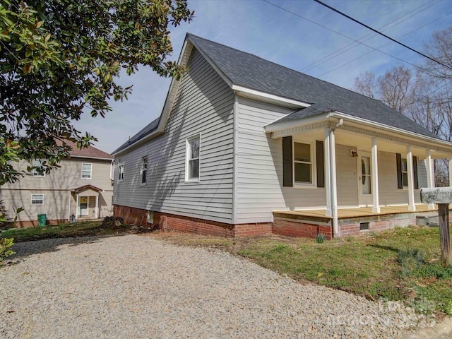 view of front facade featuring a shingled roof, covered porch, and crawl space