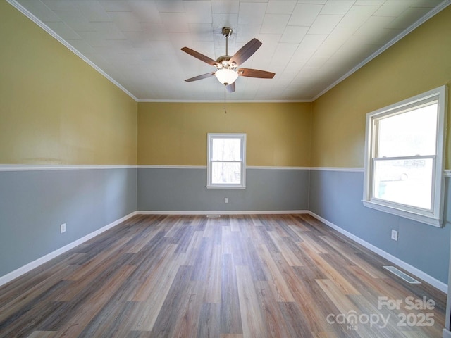 unfurnished room featuring baseboards, visible vents, a ceiling fan, ornamental molding, and wood finished floors