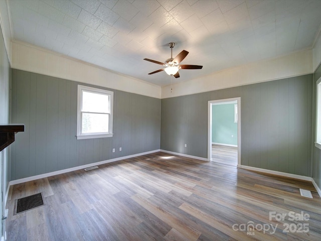 empty room featuring wood finished floors, visible vents, and baseboards