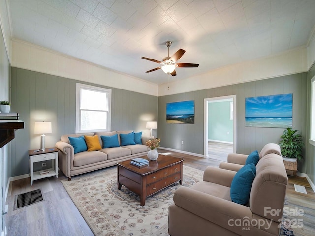 living area featuring light wood finished floors, visible vents, baseboards, and a ceiling fan
