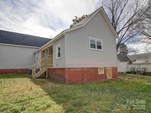 view of side of home with entry steps and a lawn