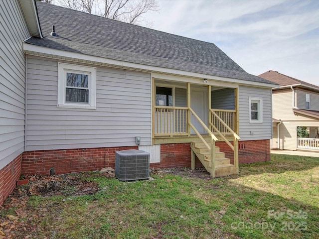 back of property with a shingled roof, a porch, cooling unit, and a yard