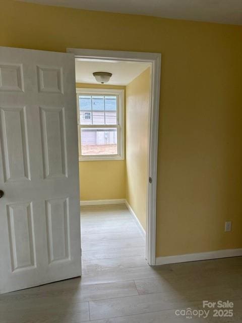 hallway featuring light wood-type flooring and baseboards