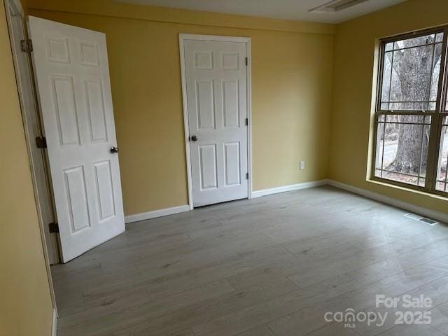 unfurnished bedroom with baseboards, visible vents, and light wood-style floors