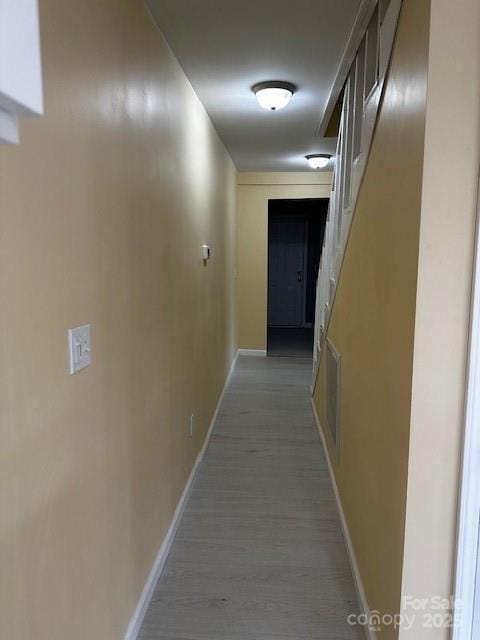 hallway with light wood-style floors, visible vents, and baseboards