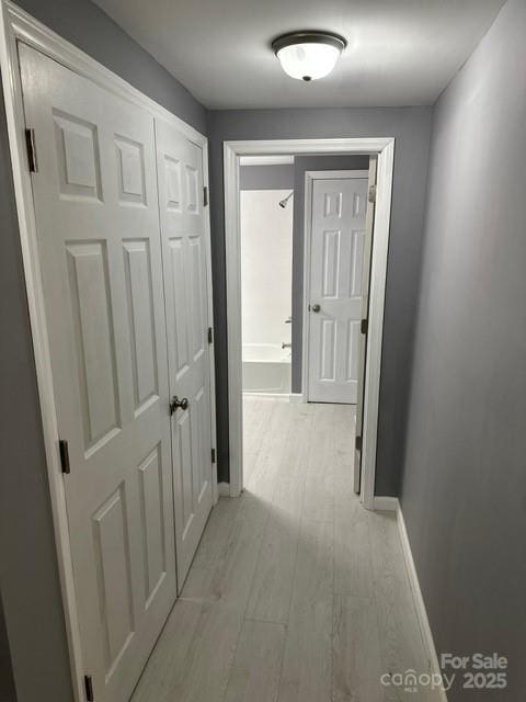 hall with light wood-type flooring and baseboards