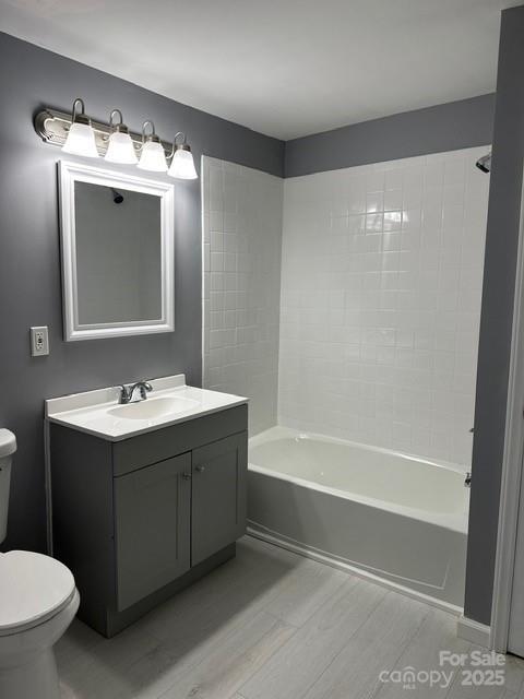 full bath with wood finished floors, vanity, toilet, and shower / bathtub combination