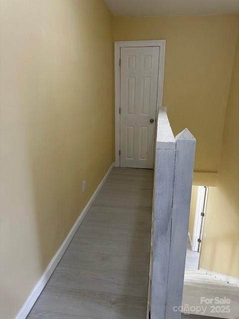 hall with light wood-style floors and baseboards