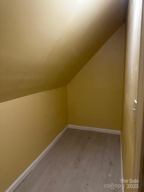 bonus room featuring vaulted ceiling, baseboards, and wood finished floors