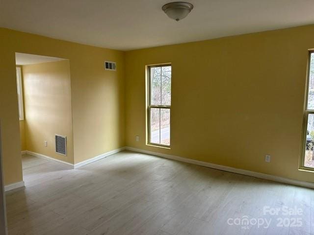 empty room featuring baseboards, visible vents, and light wood-style floors