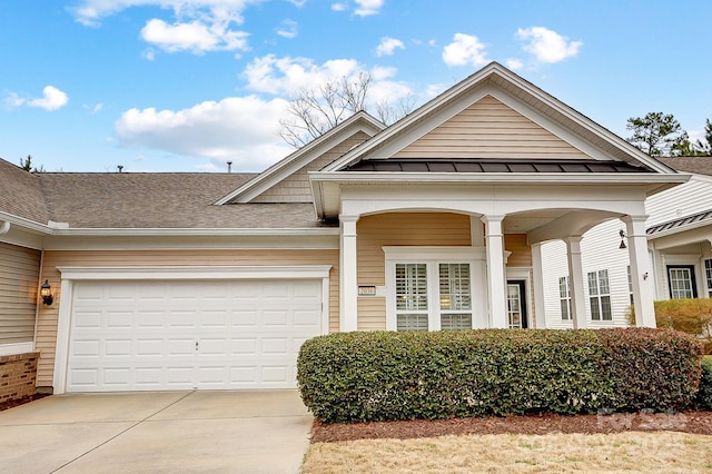 view of front facade with a garage, driveway, a shingled roof, and a standing seam roof