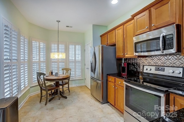 kitchen featuring visible vents, appliances with stainless steel finishes, brown cabinets, pendant lighting, and backsplash