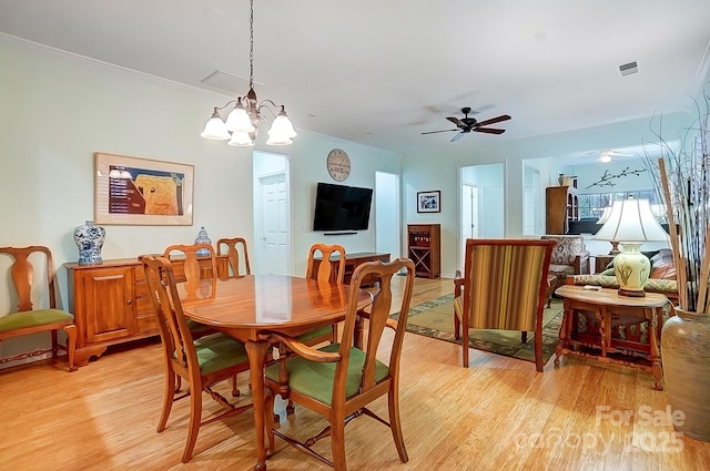 dining area with crown molding, a ceiling fan, visible vents, and light wood-style floors