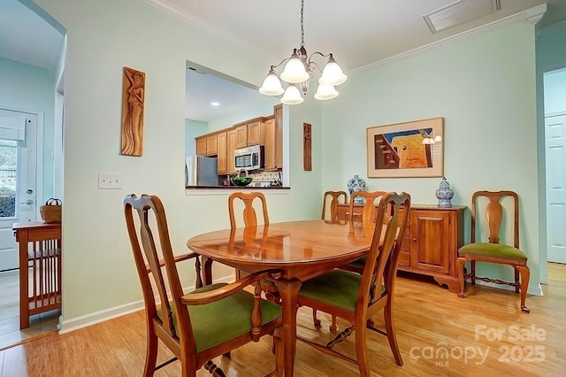 dining area with crown molding, a notable chandelier, light wood finished floors, visible vents, and baseboards