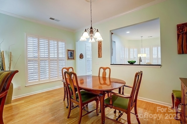 dining room featuring light wood-type flooring, visible vents, baseboards, and crown molding