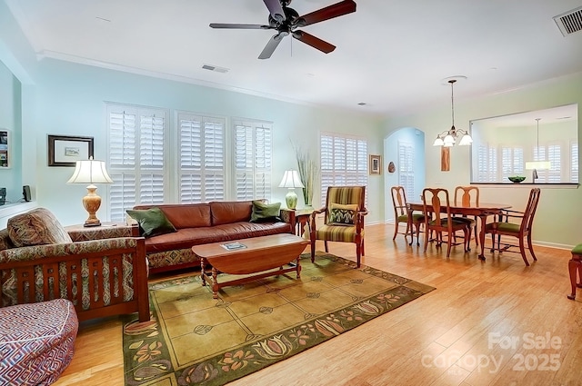 living area with light wood-type flooring, visible vents, and ornamental molding