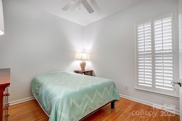 bedroom featuring a ceiling fan, baseboards, and wood finished floors