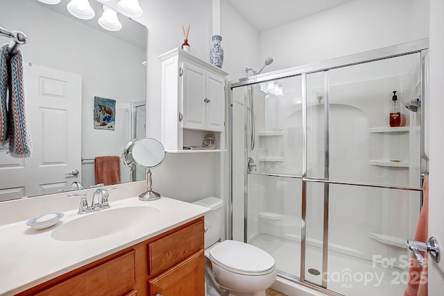 full bathroom featuring a stall shower, vanity, and toilet