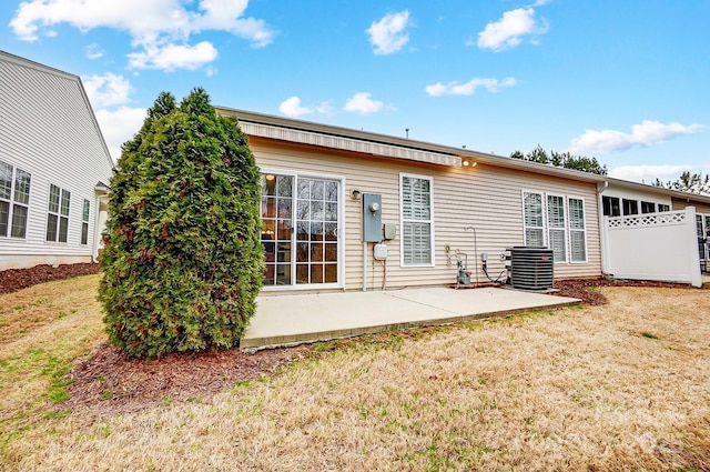 back of property with central air condition unit, a patio area, and a yard