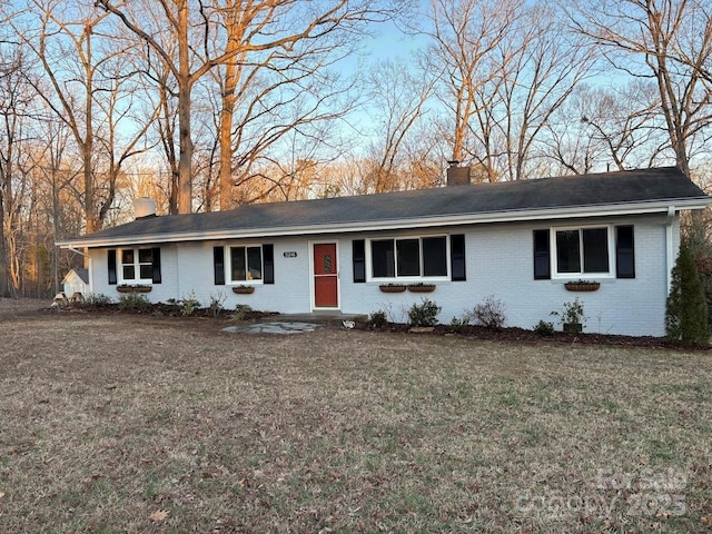 single story home featuring brick siding, a chimney, and a front lawn