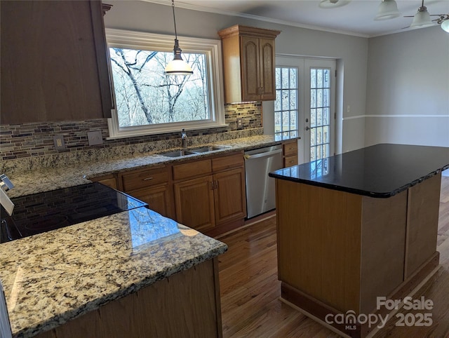 kitchen with dark wood-type flooring, a sink, a kitchen island, dishwasher, and crown molding