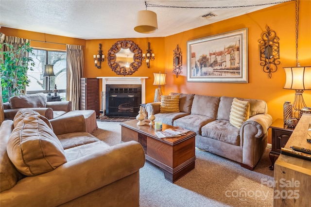 living room with carpet floors, a fireplace with flush hearth, visible vents, and a textured ceiling